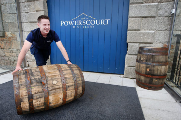 Powerscourt distillery man rolling a barrel