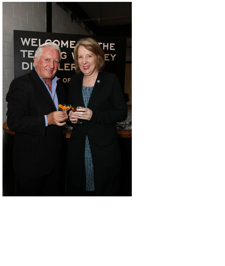 man and woman standing at event with glasses in their hands